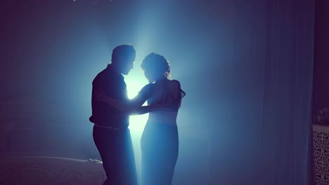 Young-couple-dance-in-a-dark-room-with-smoke.-Slow-motion.-Silhouette