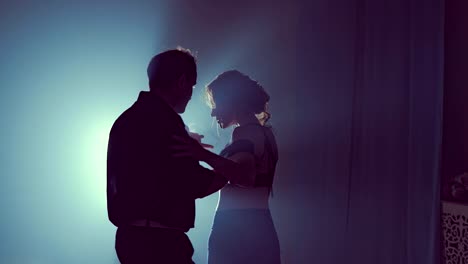Woman-and-man-are-pressed-against-each-other-and-dancing-in-ballroom.-Slow-motion.-Silhouette