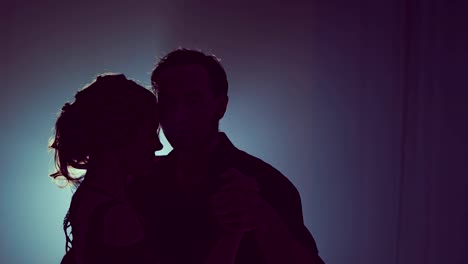 Woman-and-man-are-pressed-against-each-other-and-dancing-in-ballroom.-Slow-motion.-Silhouette