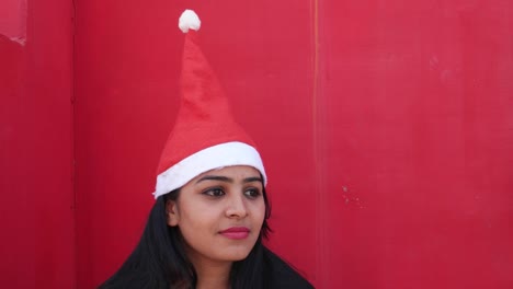 Close-up-portrait-of-young-Indian-girl-with-Santa's-hat-making-faces-towards-the-camera,-excited-and-extremely-happy