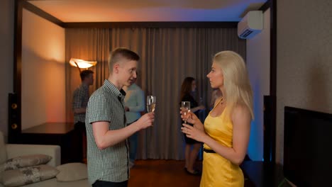 Young-couple-have-private-conversation-and-flirt-at-glamorous-party-drinking-champagne-cocktail