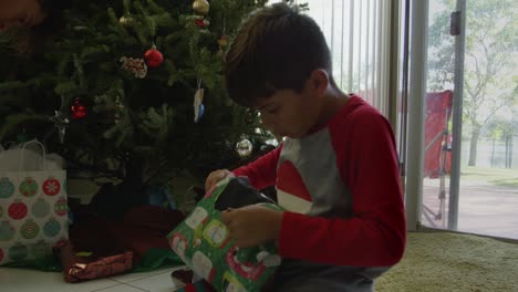 Slow-motion-of-a-boy-opening-gift-on-Christmas-day,-but-not-sure-of-what-it-is