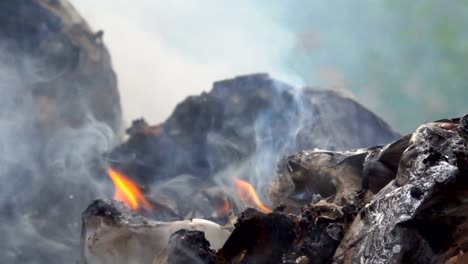 Slow-motion-smoke-of-fire-burning-garbage-on-dark-background.