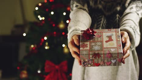 Muchacha-con-sombrero-de-la-Navidad-hace-deseos-y-abre-un-paquete-de-regalo-de-Navidad.-concepto-de-vacaciones-y-año-nuevo.-la-niña-es-feliz-y-sonríe-de-la-mano-con-el-regalo-de-Navidad.