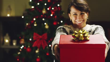 Girl-with-Christmas-hat-makes-wishes-and-opens-a-Christmas-gift-package.-concept-of-holidays-and-new-year.-the-girl-is-happy-and-smiles-with-christmas-gift-in-hand.