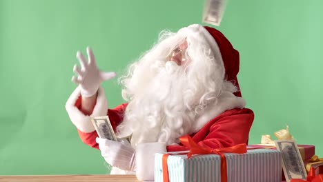 Satisfied-Santa-Claus-throwing-bills-out-of-a-bundle-money-on-table,-money-on-table,-chromakey-in-the-background