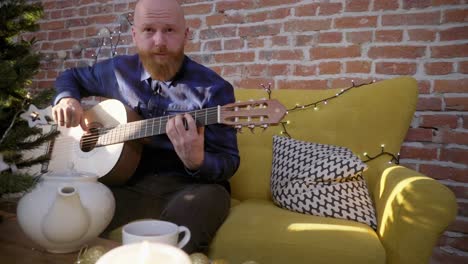 Mann-spielt-Gitarre-neben-Weihnachtsbaum