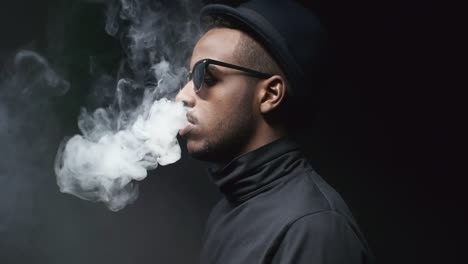 Hombre-negro-fresco-en-gafas-de-sol-exhalando-humo