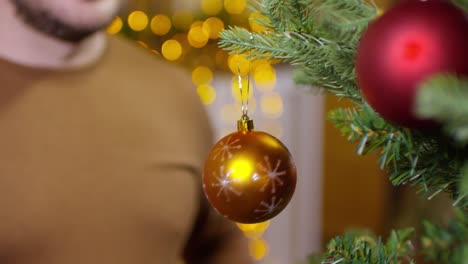 Man-Hanging-Decorative-Bauble-on-Christmas-Tree