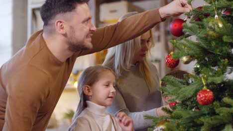 Mutter-und-Vater-dekorieren-Weihnachtsbaum-mit-kleinen-Kindern