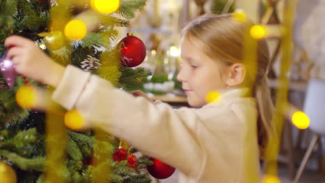 Entzückende-kleine-Mädchen-schmücken-Weihnachtsbaum-mit-Girlande