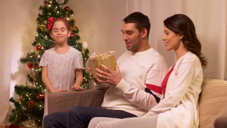 glückliche-Familie-mit-Weihnachtsgeschenk-zu-Hause