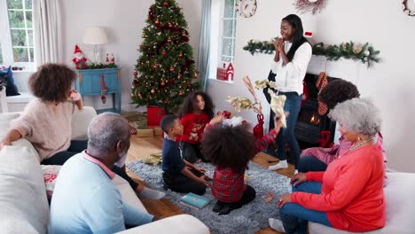 Niños-lanzando-papel-de-embalaje-en-el-aire-como-generación-de-Multi-familia-celebran-la-Navidad-juntos