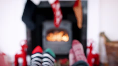 Low-section-of-coupleÕs-feet-in-front-of-a-fireplace,--hands-raising-their-glasses-to-make-a-toast,-detail