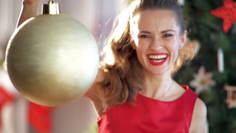 housewife-near-Christmas-tree-spinning-big-gold-Christmas-ball