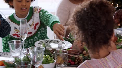 Multi-Generation-mixed-Race-Familie-an-Weihnachten-Abendessen-am-Tisch-essen-zusammen-sitzen-panning-shot