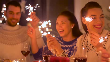 happy-friends-with-sparklers-having-christmas-dinner-at-home