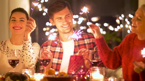 happy-friends-with-sparklers-having-christmas-dinner-at-home