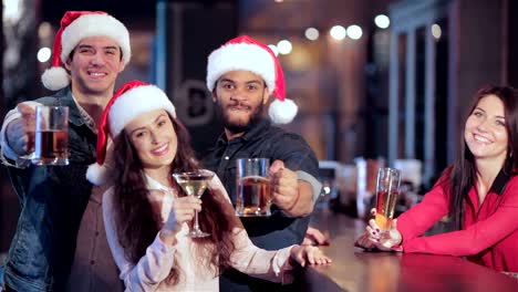 Three-friends-in-Santa-hats-and-the-girl-behind-the-bar-with-a-glass-of-beer