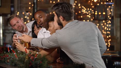 Freunde-machen-einen-Toast-auf-einer-Weihnachtsfeier-in-einer-bar