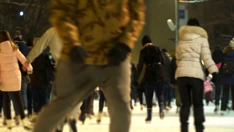 Concepto-de-amistad-y-amor.-Multitud-en-la-pista-de-patinaje-de-la-ciudad-de-la-noche.-Nieve-que-cae