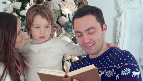 Happy-family-of-three-reading-together-on-Christmas-evening