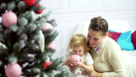 Happy-young-mother-playing-with-her-sweet-baby-in-a-decorated-room-near-the-christmas-tree