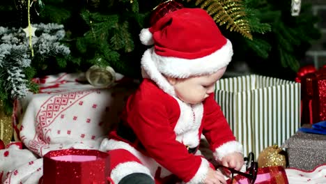 Santa-Claus-niño,-niño-en-traje-de-Santa,-jugar-con-gafas,-niño-se-sienta-en-el-carnaval-de-disfraces,-trajes-de-la-Navidad-bajo-el-árbol-de-Navidad