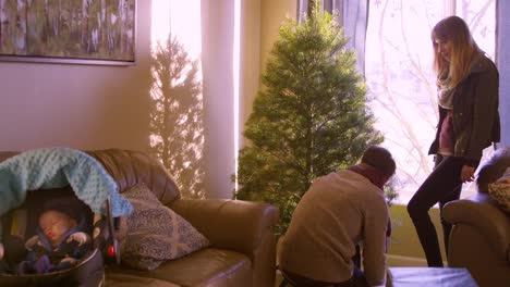 Baby-sleeps-in-her-carseat-on-the-couch-while-mom-and-dad-set-up-the-Christmas-tree