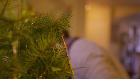 Primer-plano-de-un-hombre-poniendo-un-adorno-de-copo-de-nieve-en-un-árbol-de-Navidad