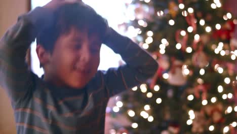 Boy-dances-with-tiny-santa-hat-on-and-then-places-it-on-a-miniature-christmas-tree