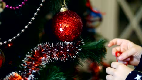 Nahaufnahme-der-Kinderhände-Mädchen-schmücken-einen-Weihnachtsbaum-mit-leuchtend-bunten-Weihnachts-Spielzeug,-Kugeln