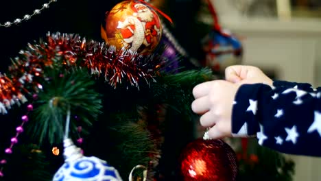 Primer-plano-de-las-manos-de-niña-de-niño-están-decorando-un-árbol-de-Navidad-con-brillantes-coloridos-juguetes-de-Navidad,-bolas