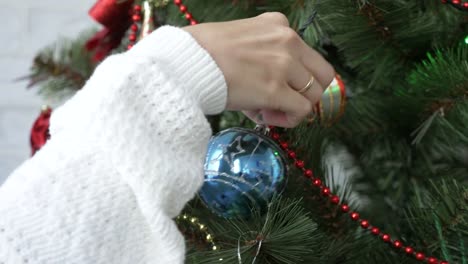 Close-up-of-girl-hand-decorate-christmas-tree-at-daylight