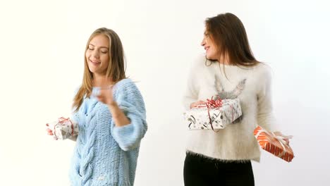 Two-pretty-girls-dances-and-gives-presents-to-each-other-at-white-background