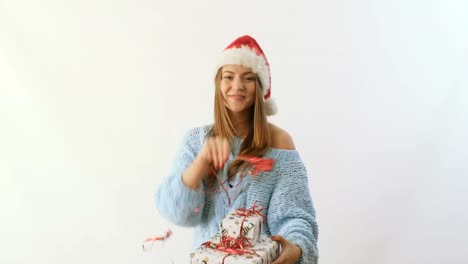 Girl-in-santa's-hat-with-gifts-waves-a-stick-with-ribbons-at-white-background