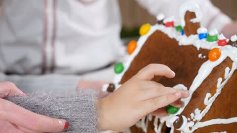 Portrait-of-cute-young-girl-decorates-a-gingerbread-house