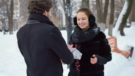 Handsome-man-presents-the-gift-to-the-woman-in-winter-park