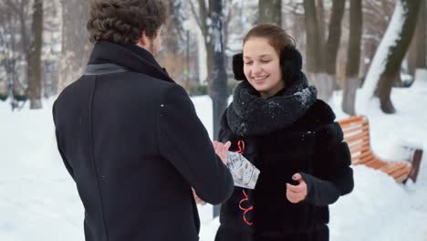 Hombre-guapo-presenta-el-regalo-a-la-mujer-en-el-parque-de-invierno