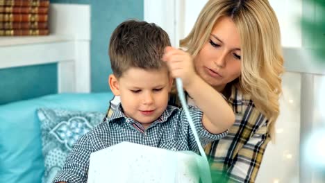 Happy-little-boy-open-Christmas-gift-box-with-mom