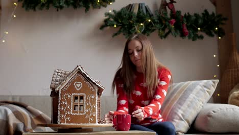 Schöne-Frau-mit-Winteroutfit-Teetrinken-mit-Lebkuchen-zu-Hause-in-der-Nähe-von-Christmas-tree