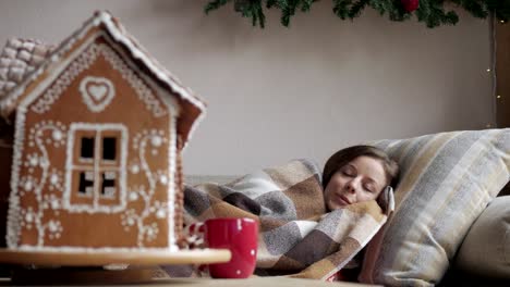 liegend-auf-dem-Sofa-unter-einer-Decke.-Gesundheit-und-Krankheit-Konzept---kranke-Frau-mit-Tasse-Tee.-Weihnachtsmorgen.