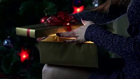 La-chica-abre-un-regalo-junto-al-árbol-de-Navidad.