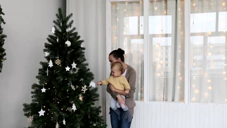 Baby-boy-with-mother-decorates-the-Christmas-tree