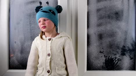 Kleine-Mädchen-sitzt-auf-der-Fensterbank-hinter-dem-gefrorenen-Fenster.