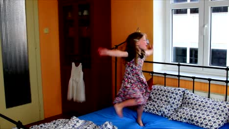 Cute-little-girl-dances-on-a-bed.-SLow-motion.-Childhood-concept