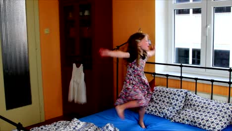 Lindo-poco-bailes-de-niña-en-una-cama.-Cámara-lenta.-Concepto-de-infancia