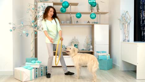 girl-with-a-dog-is-playing-with-a-hoop-in-room-with-Christmas-decorations