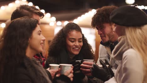 Gruppe-von-Freunden-trinken-Glühwein-am-Weihnachtsmarkt