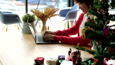 asian-woman-use-computer-at-home.-girl-with-xmas-tree-at-christmas-holiday.-new-year-celebration.-season-greetings